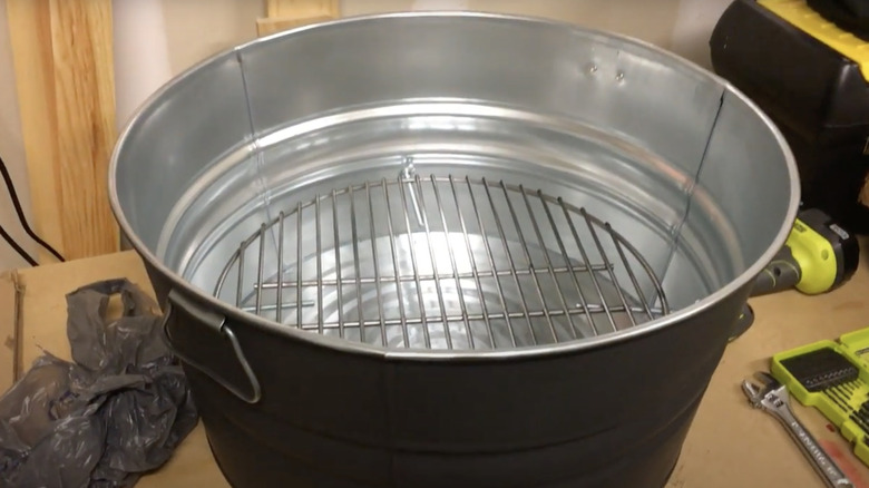 A metal wash tub with a grill plate fitted inside it.