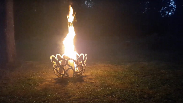 A fire blazes in a fire pit made from old horseshoes welded together to form a bowl.