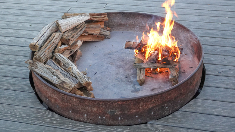 An old rusty stock tank with holes drilled in the sides is used as a large fire pit.
