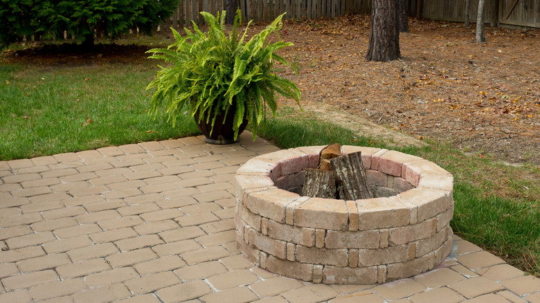 Leftover pavers made into a circular fire pit on a patio in a residential backyard.