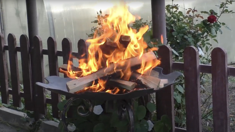 A large fire burns in a fire pit made from an up-cycled plow disc.