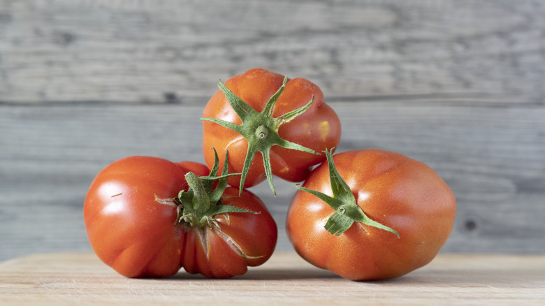 Red 'Mortgage Lifter' tomatoes grouped together on a wooden table