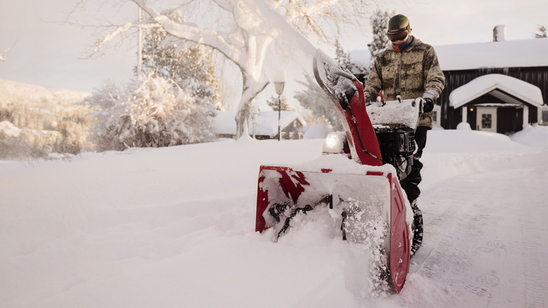A person clearing a driveway with a snow blower