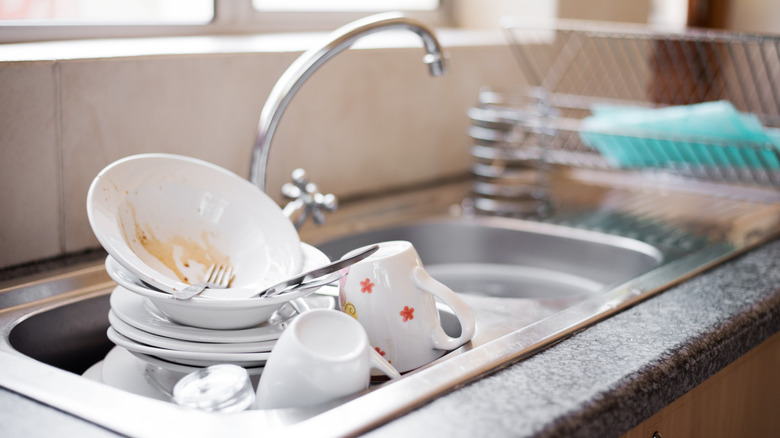 A sink full of dirty white dishes