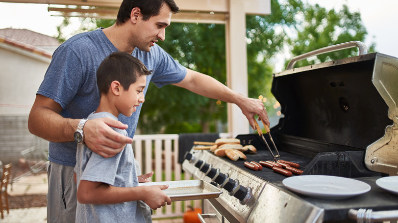 father teaching son to grill