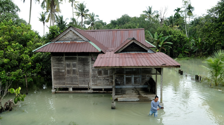 man leaving house above floodwaters