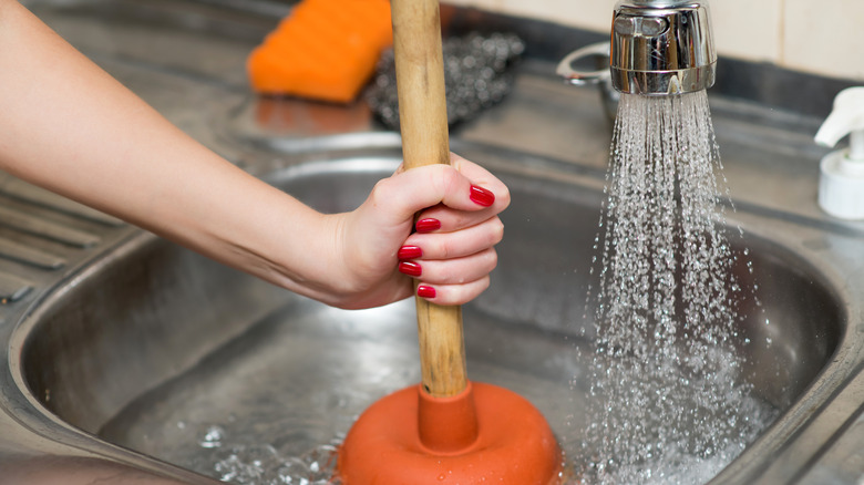 person using plunger on sink