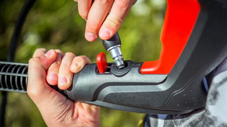 hands assembling red pressure washer