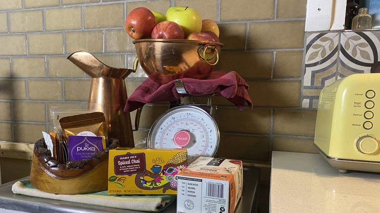 A scale and bowl of apples hiding an old oven receptacle