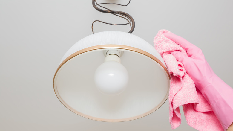 person cleaning light fixture
