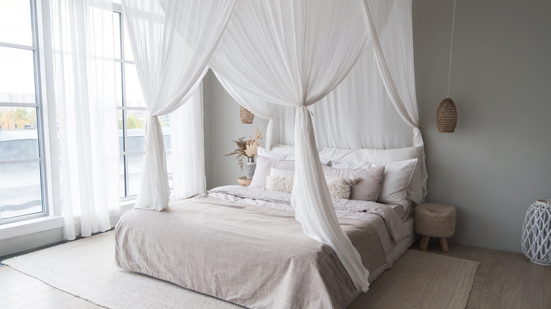 A large bed with a white canopy curtain above it.