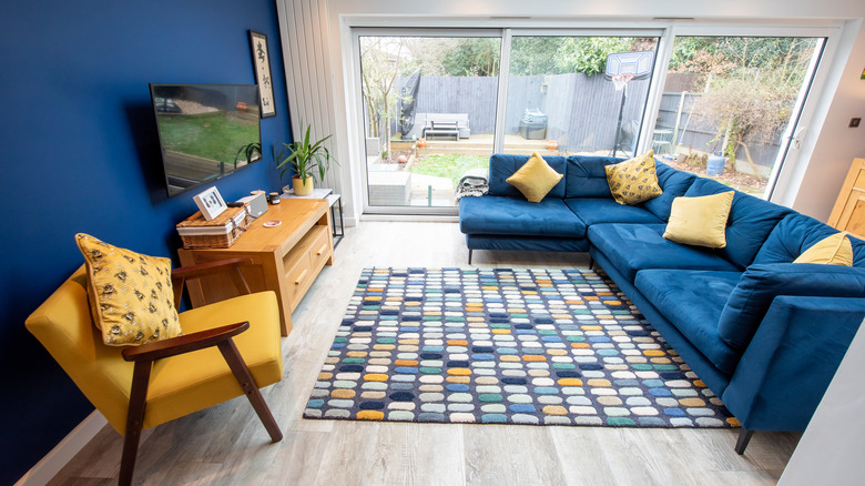 A blue and yellow styled living room with rug and tv.