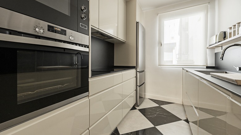 White lacquered cabinets in a black and white kitchen.