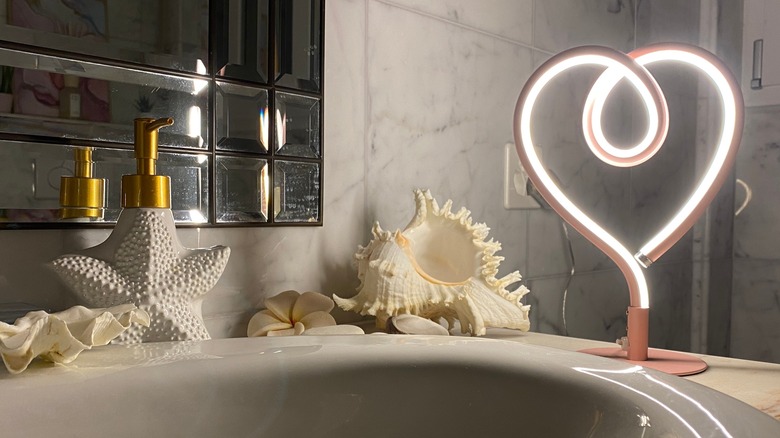 Seashell bathroom decor next to heart lamp.