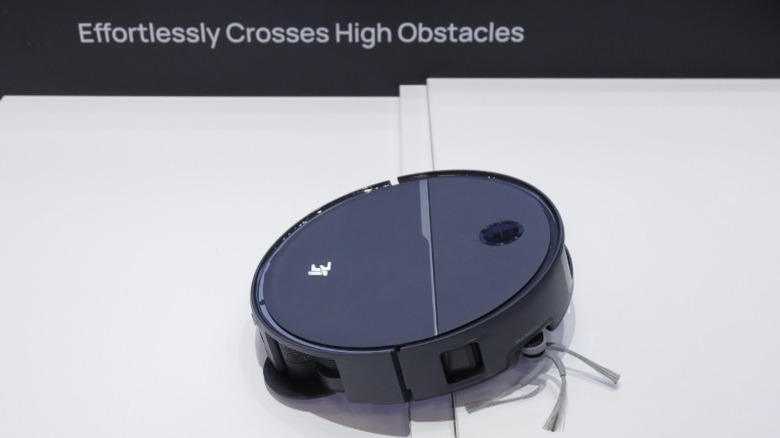 A robotic vacuum in the kitchen next to a golden retriever