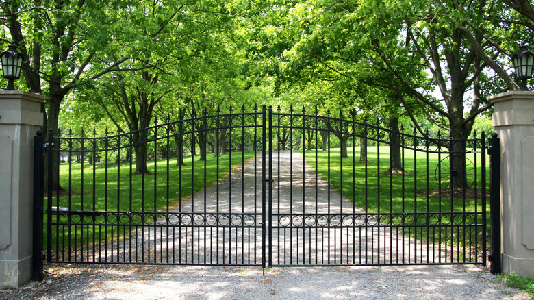 Wrought iron gate closed with stone driveway in background