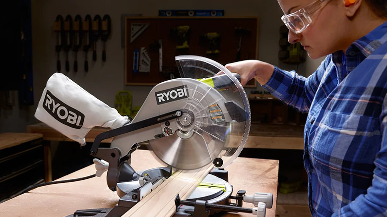 A woman using the Ryobi 10 in. Compound Miter Saw to cut a piece of wood in a workshop