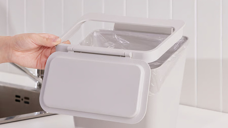Person putting lid on trash can