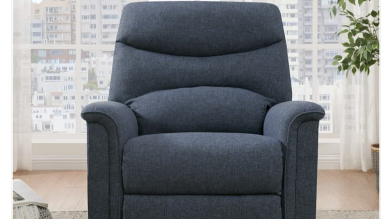 A gray recliner placed against a wide window with sheer curtain.
