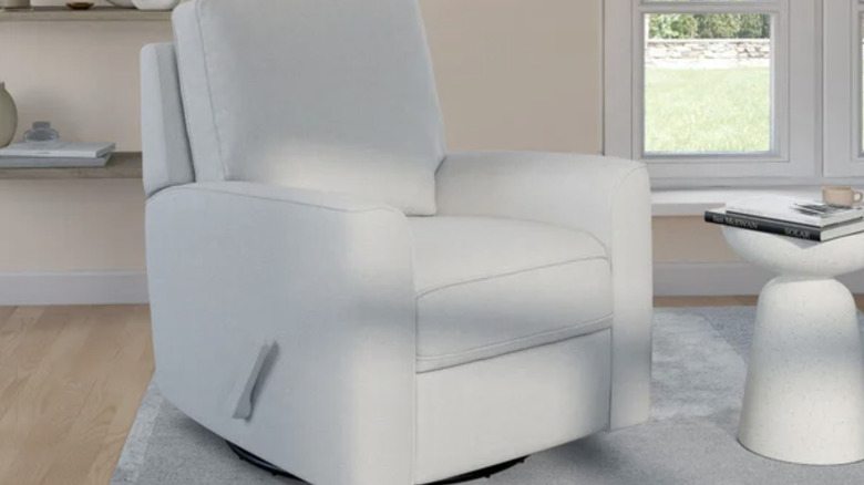 A compact light gray recliner placed in the middle of a white-themed modern living room.