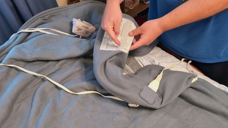 a person pointing to the label of an electric blanket