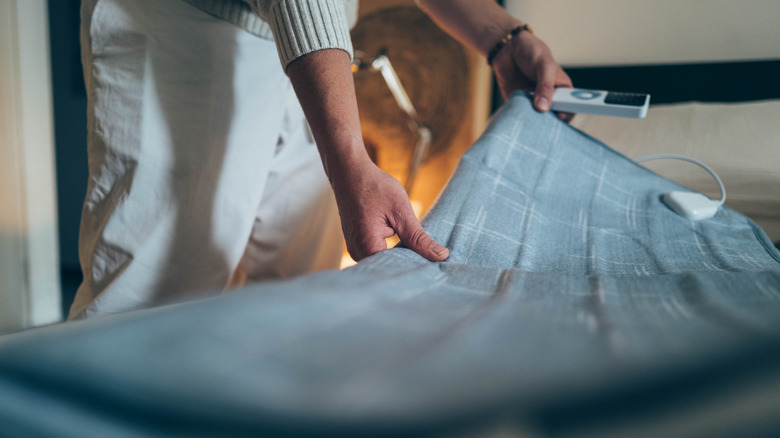a person setting an electric blanket on the bed