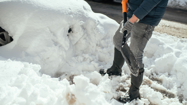 Close up of man using shovel to scrape snow off car