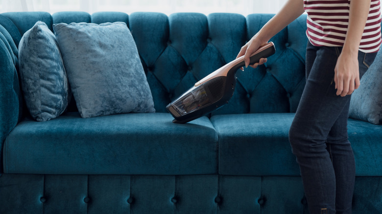 woman vacuuming a blue couch