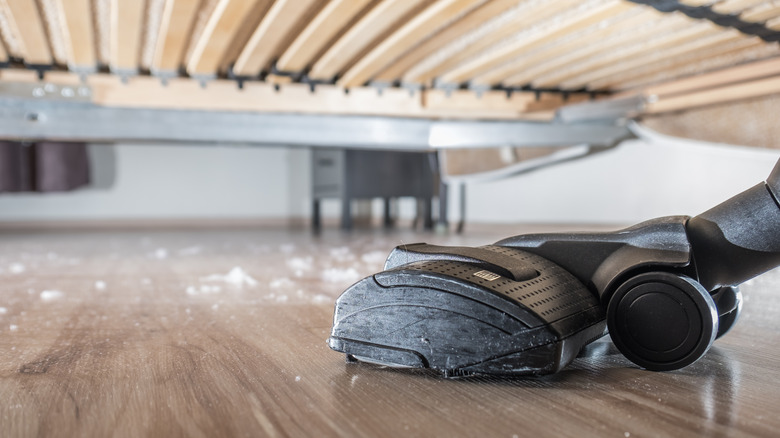 dust under bed being vacuumed