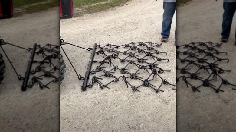 A Vevor chain drag harrow attached to an ATV sits on a gravel driveway.