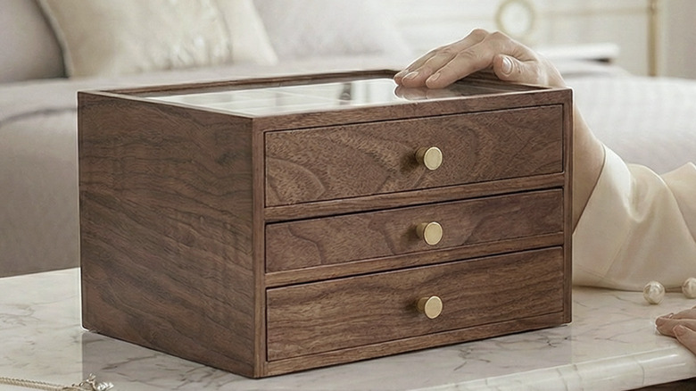 A dark wooden CHOSIN jewelry box with three drawers with gold knobs