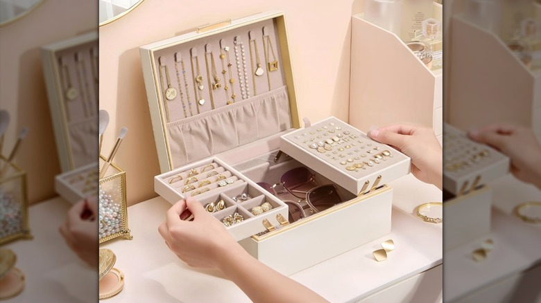 White Lolalet jewelry box being opened up with sunglasses, rings, and necklaces inside