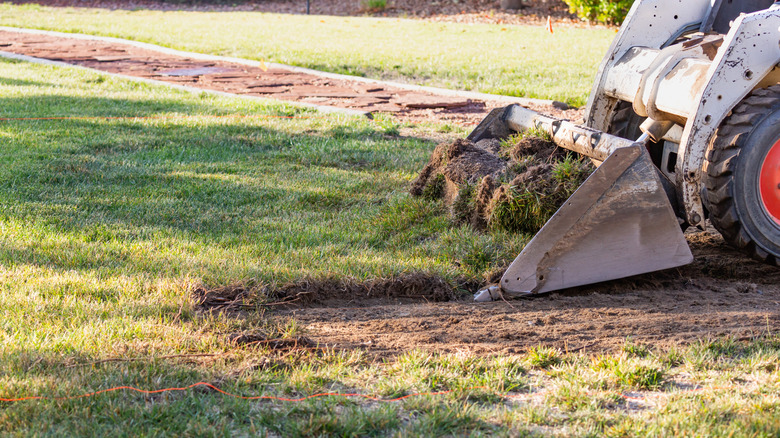 Turfgrass being removed from lawn by heavy machinery