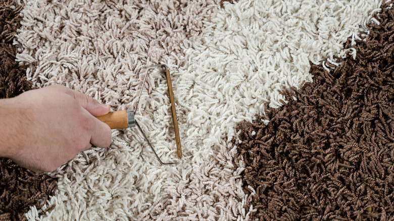A manual fabric shaver on a rug.