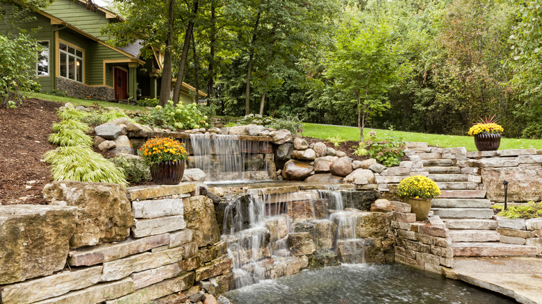 Waterfall is built into retaining wall and spills into a pond.