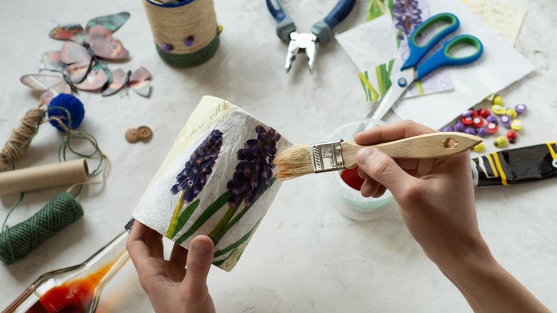 hands decoupaging jar with flowers