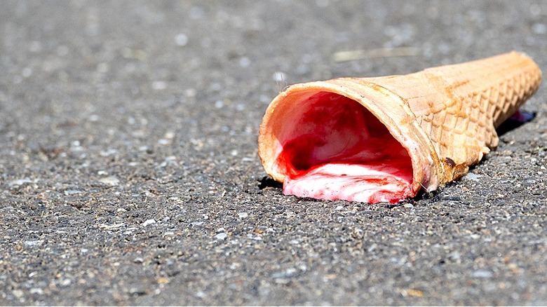 An ice cream cone melting on hot asphalt
