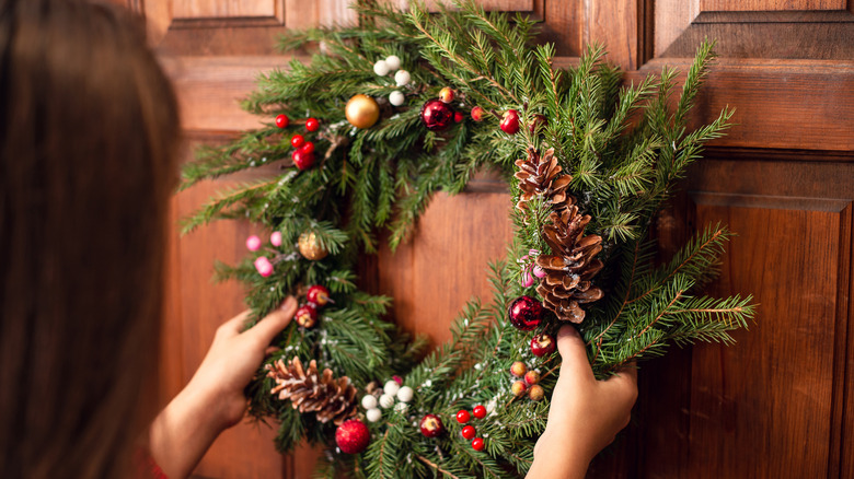 woman hanging wreath on door