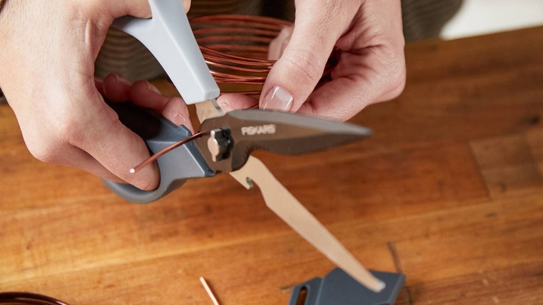 a person using Fiskars utility scissors to cut wire