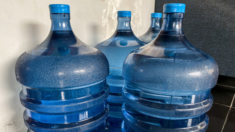 Three 5-gallon water jugs on the ground