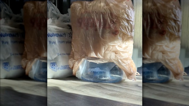 Plastic bags stacked on top of a water jug