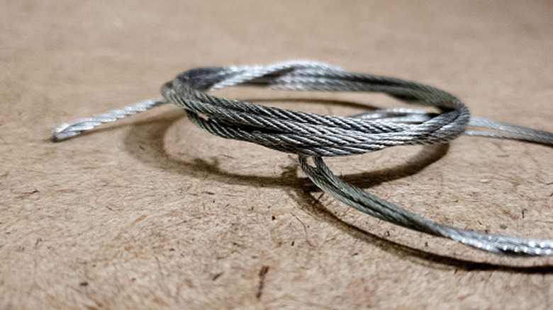 A braided metal cord on a scratched surface.