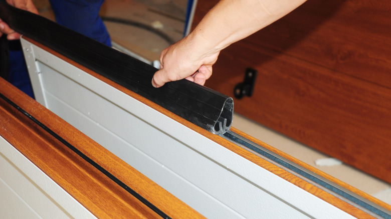 A weatherstrip being installed on a garage door.