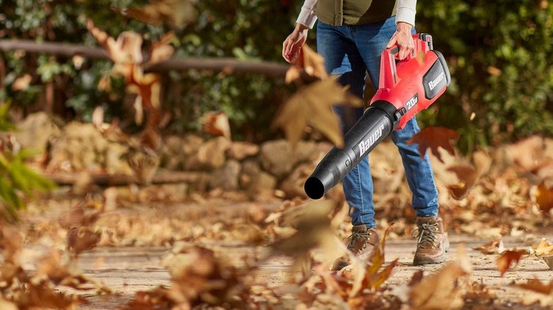 A woman in a puffer vest using the Bauer jet fan blower to clear fall leaves