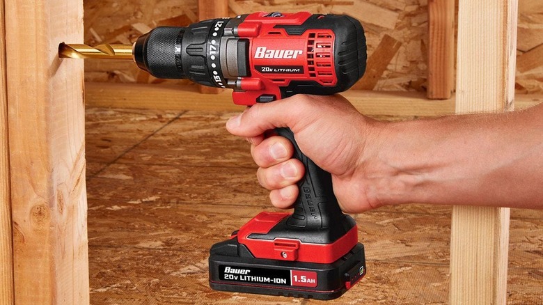 A person drilling a hole into a piece of wood with the Bauer cordless drill