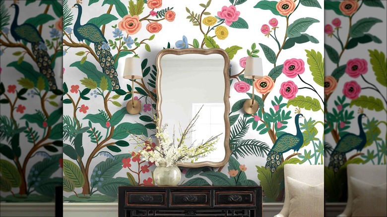 A peacock wallpaper mural is installed behind a gold mirror