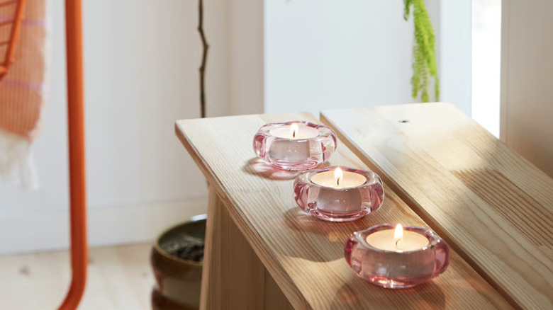 BLADFÅGEL tealight candle holder with candles burning inside on top of a table