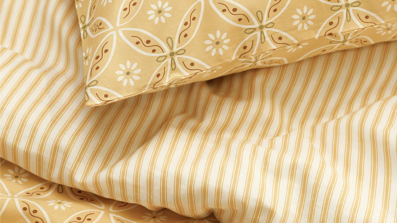 Close up of HAMNSENAP duvet cover and pillowcases with yellow geometric and floral print pattern