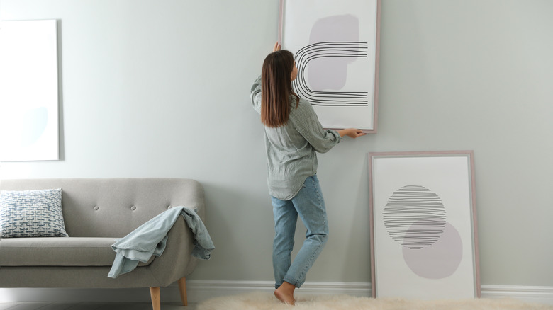 woman hanging abstract artwork