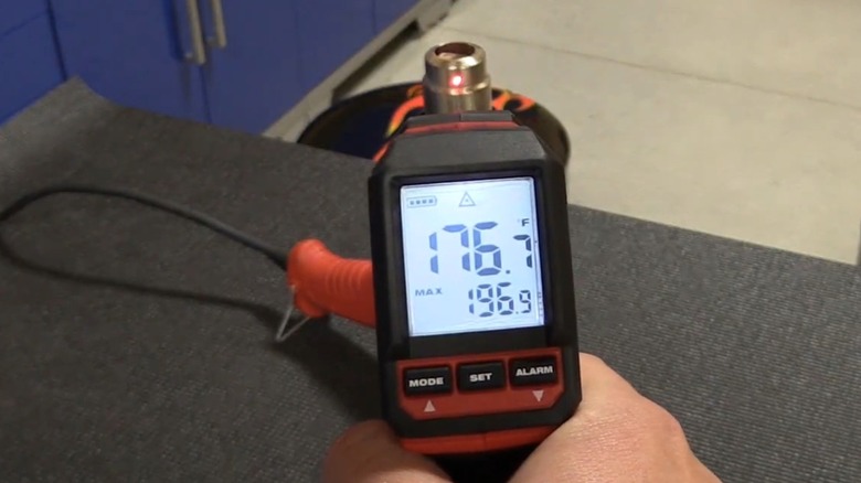 A person using an infrared thermometer on a heat gun